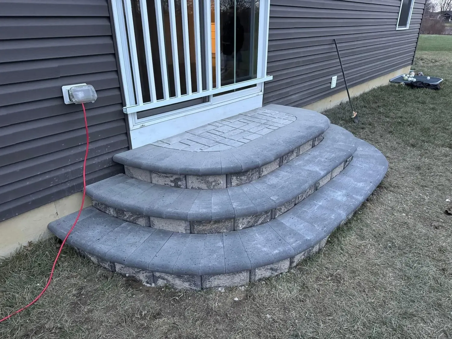 Curved paver stoop with three treads and bullnose caps at a patio door