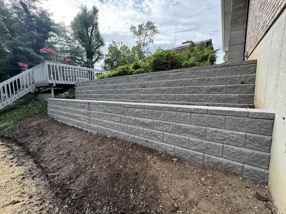 Two tier block retaining wall along a house foundation