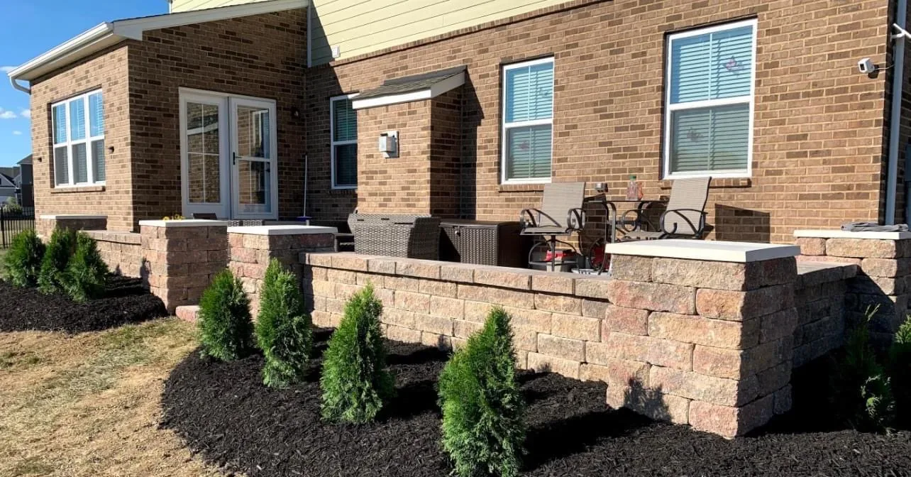 Block seating wall with pillars and white caps enclosing a brick ranch patio